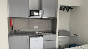 Eine kleine Küchenzeile mit Mikrowelle, Kühlschrank und Spüle.