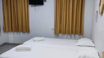 Ein Hotelzimmer mit zwei Betten, einem Flachbildfernseher, einer Klimaanlage und Vorhängen.