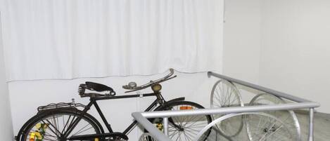 A bicycle with a basket and a seat, leaning against a white curtain.