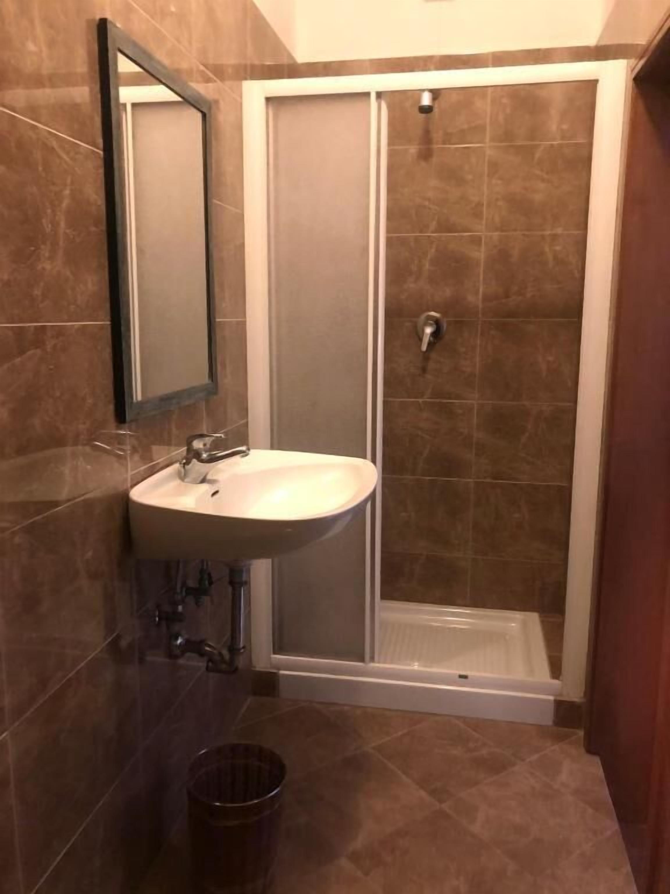 Une salle de bain avec un lavabo, un miroir, une douche et des murs carrelés.