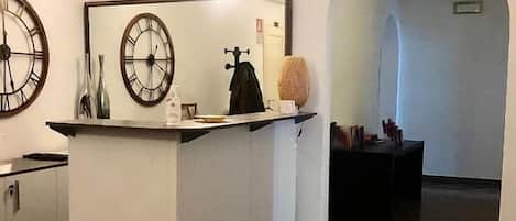 A modern interior with a central island, a large clock, and a tiled floor.