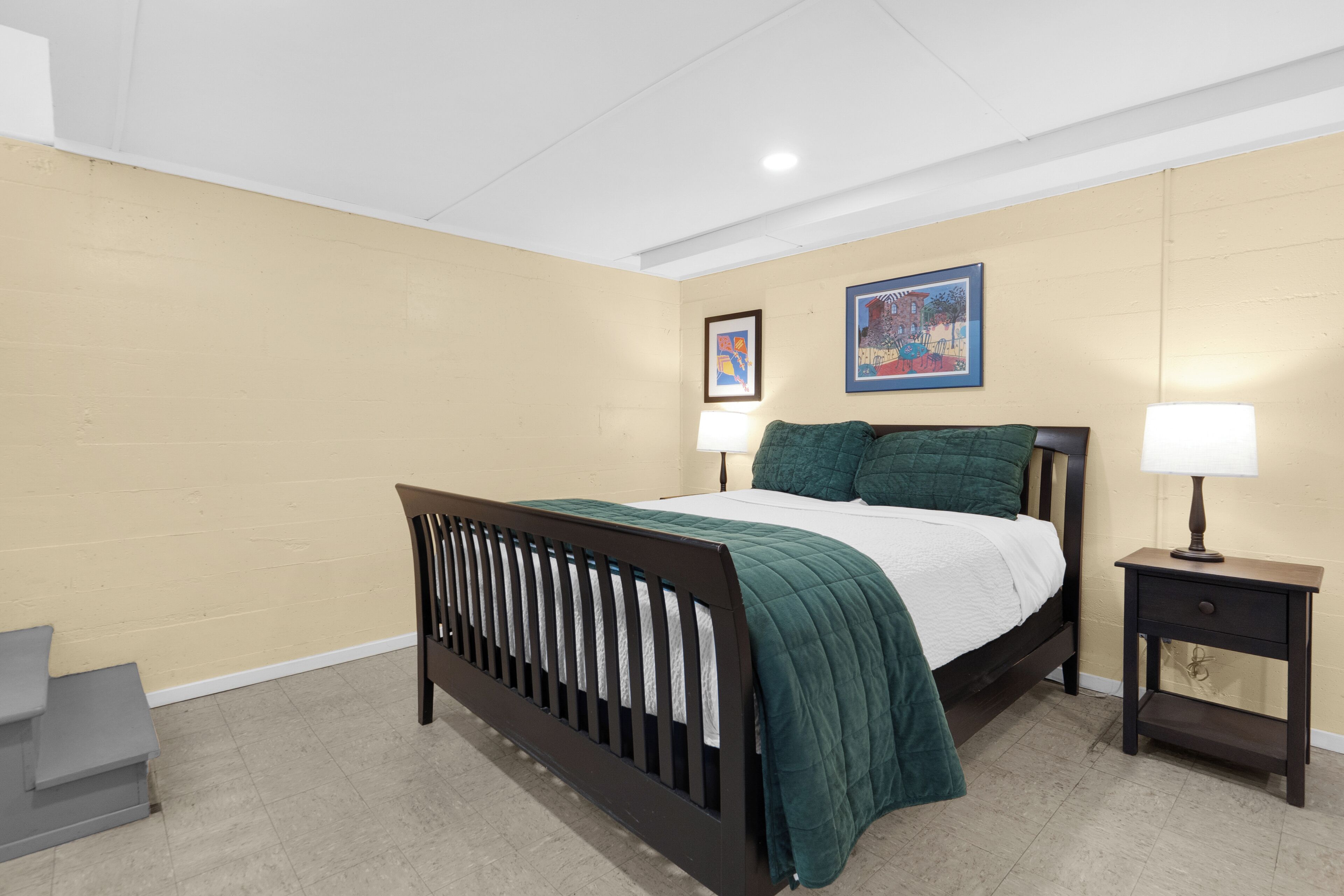 Un dormitorio con cama, mesitas de noche y decoración en la pared.