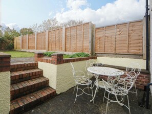 A patio with a table and chairs, a brick wall, and a wooden fence. - 15 Rose Hill (Beaumaris)