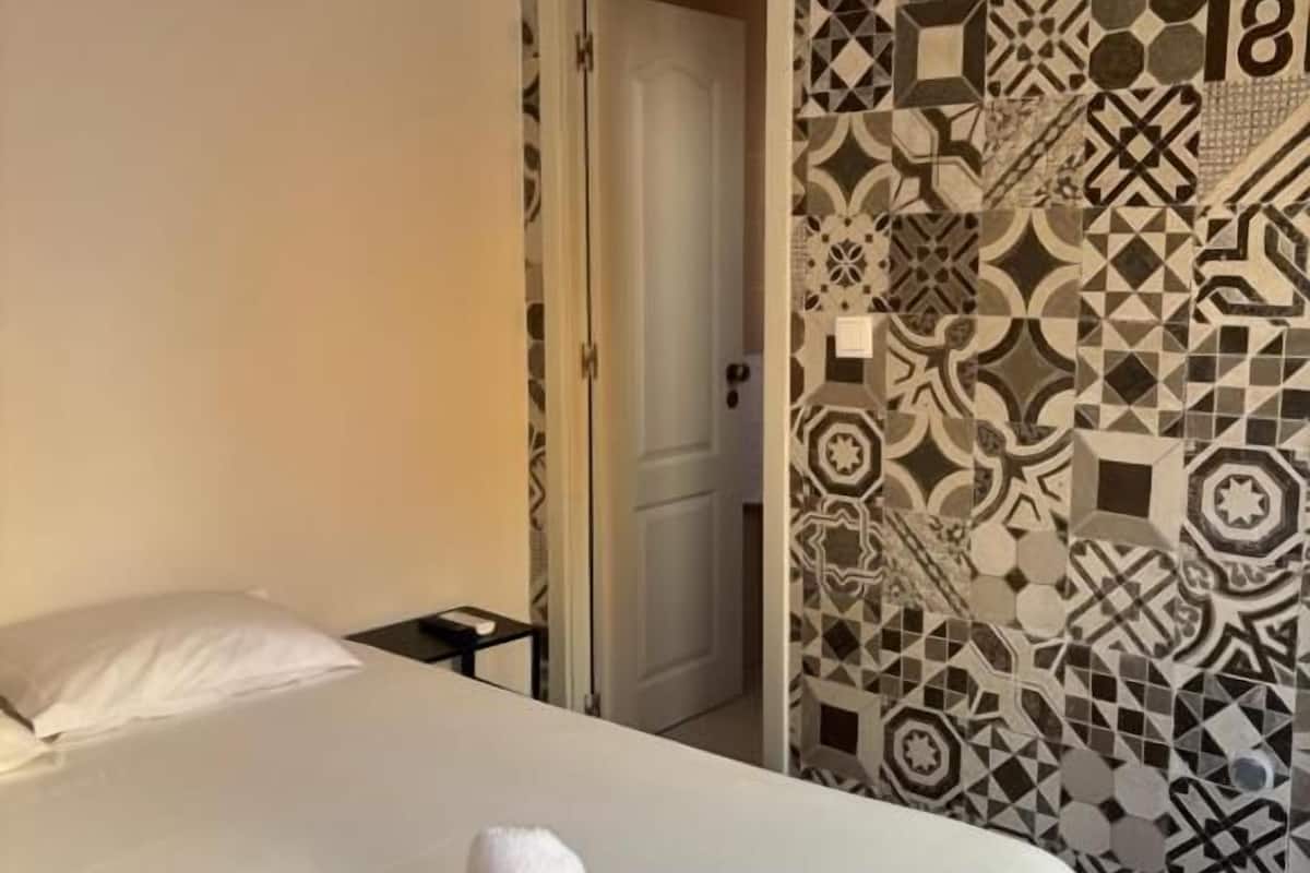 Une chambre d’hôtel avec un lit, une table de chevet et un mur orné d’un motif.