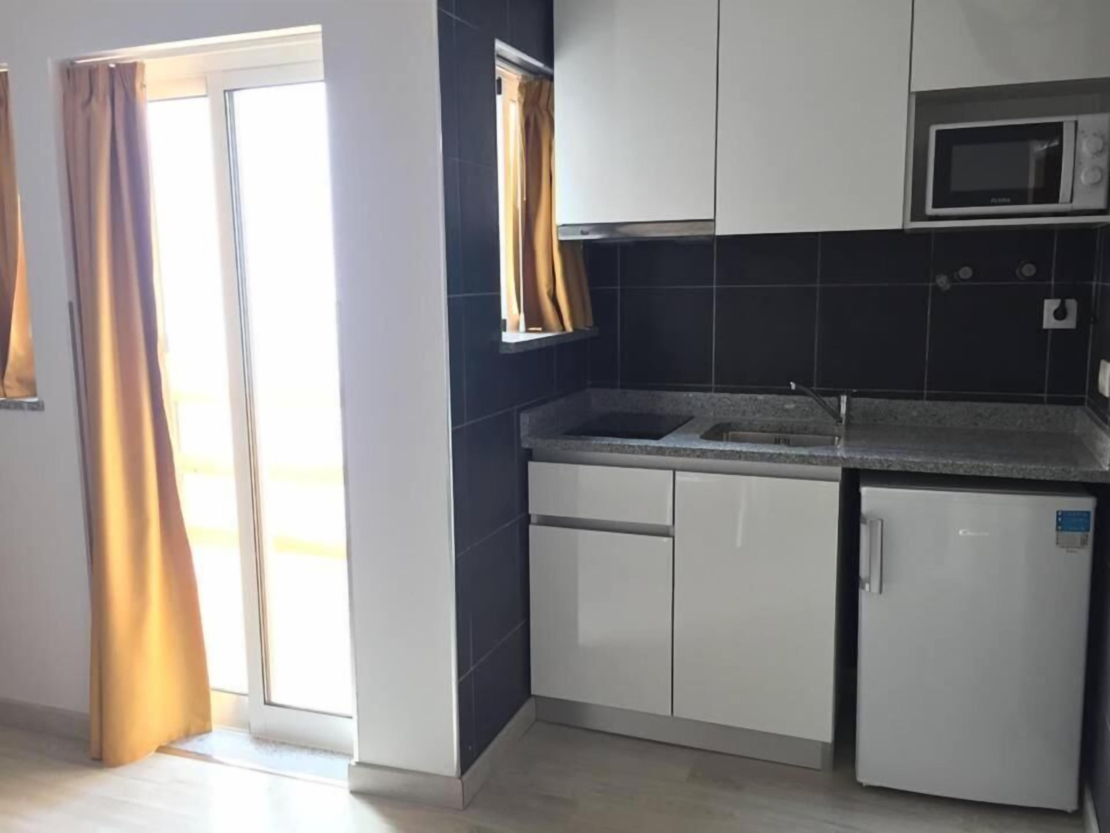 Una cocina equipada con microondas, pileta y refrigerador.