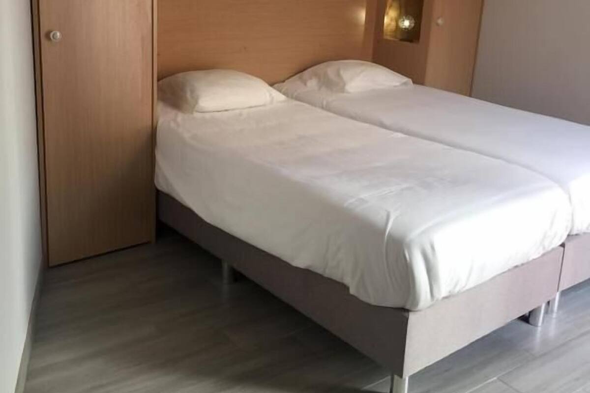 Une chambre à coucher comprenant un lit, une armoire et un luminaire fixé au mur.