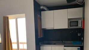 A modern kitchen with white cabinets, a microwave, and a small refrigerator.