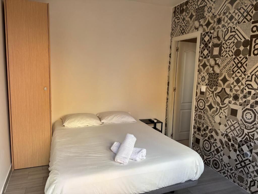 Quarto de hotel com uma cama, um guarda-roupa de madeira e parede estampada.