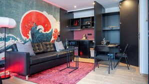 A modern living space with a black leather sofa, a red rug, and a wall mural. - DECA CONCIERGERIE (Le Muy)