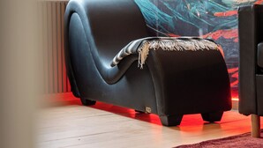 A modern lounge area with a black sofa, a red carpet, and a large abstract painting on the wall. - DECA CONCIERGERIE (Le Muy)