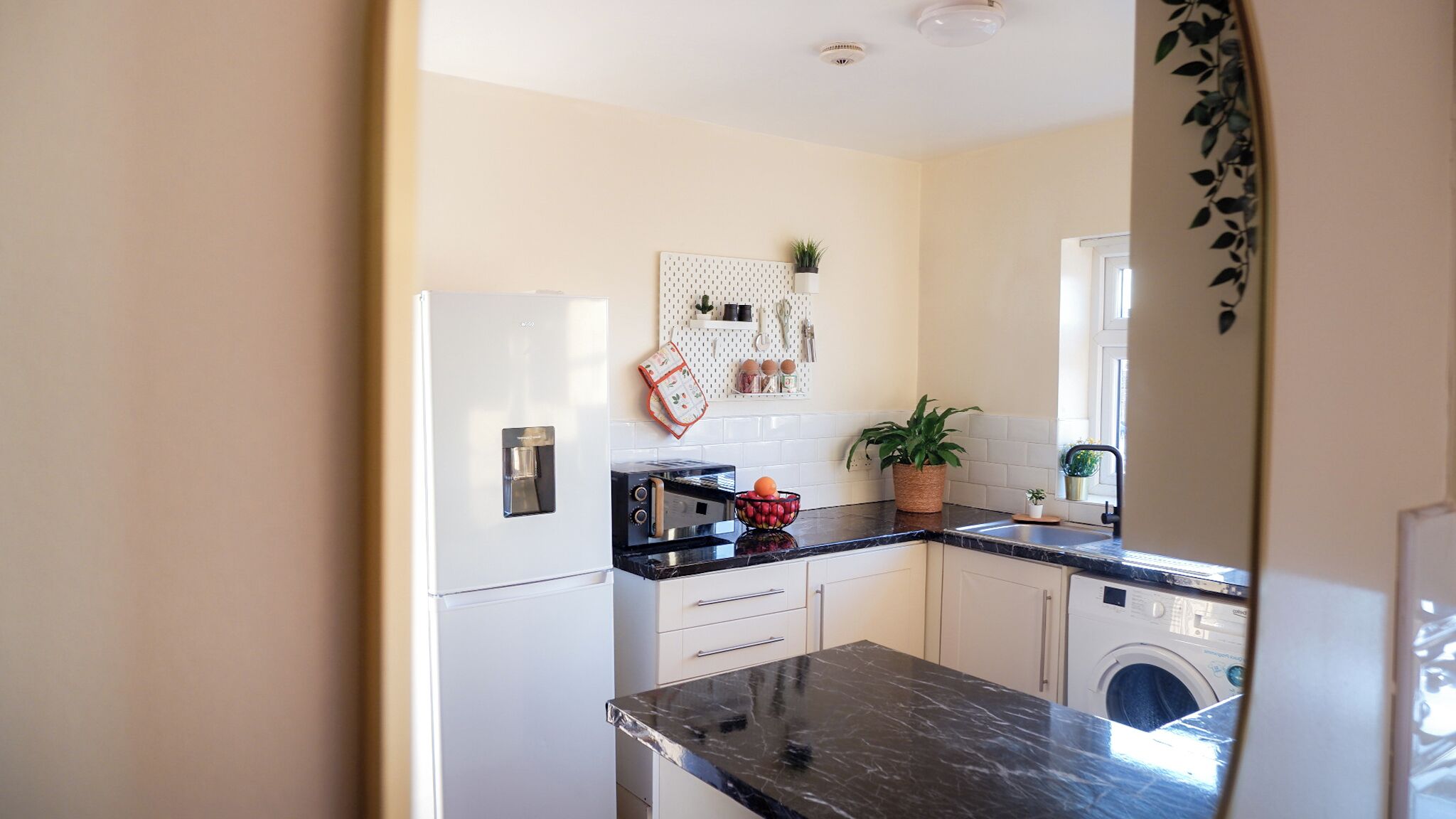 A compact kitchen with a refrigerator, a toaster, a sink, and a washing machine.