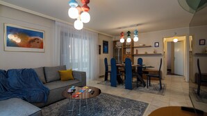 Een woonkamer met een bank, salontafel en een eethoek met stoelen en een tafel.