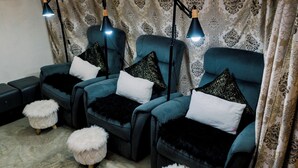 A room with three reclining chairs, each with a black and white pillow, and a pair of fluffy white poufs. - The Town  (El Nido)