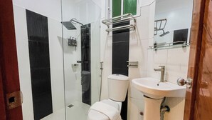 A bathroom with a glass shower enclosure, a toilet, and a sink. - The Town  (El Nido)