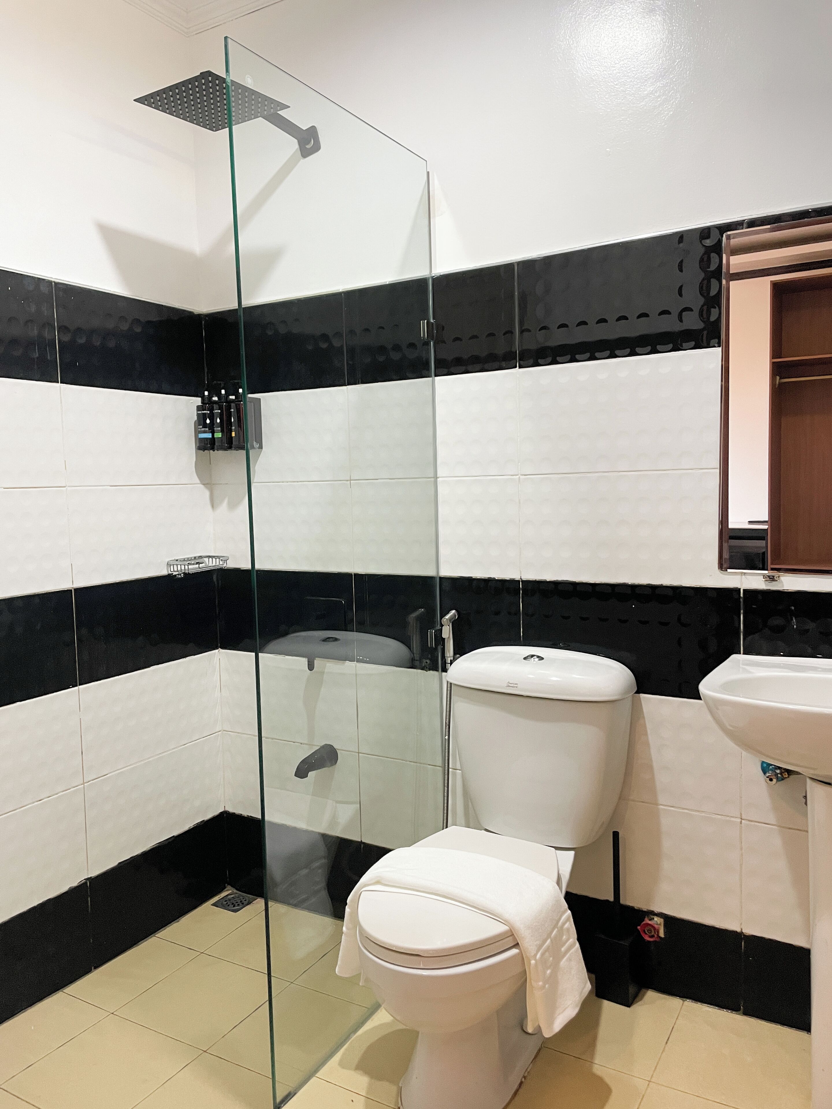 A bathroom with a glass-enclosed shower, a toilet, and a sink.