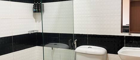 A bathroom with a glass-enclosed shower, a toilet, and a sink.