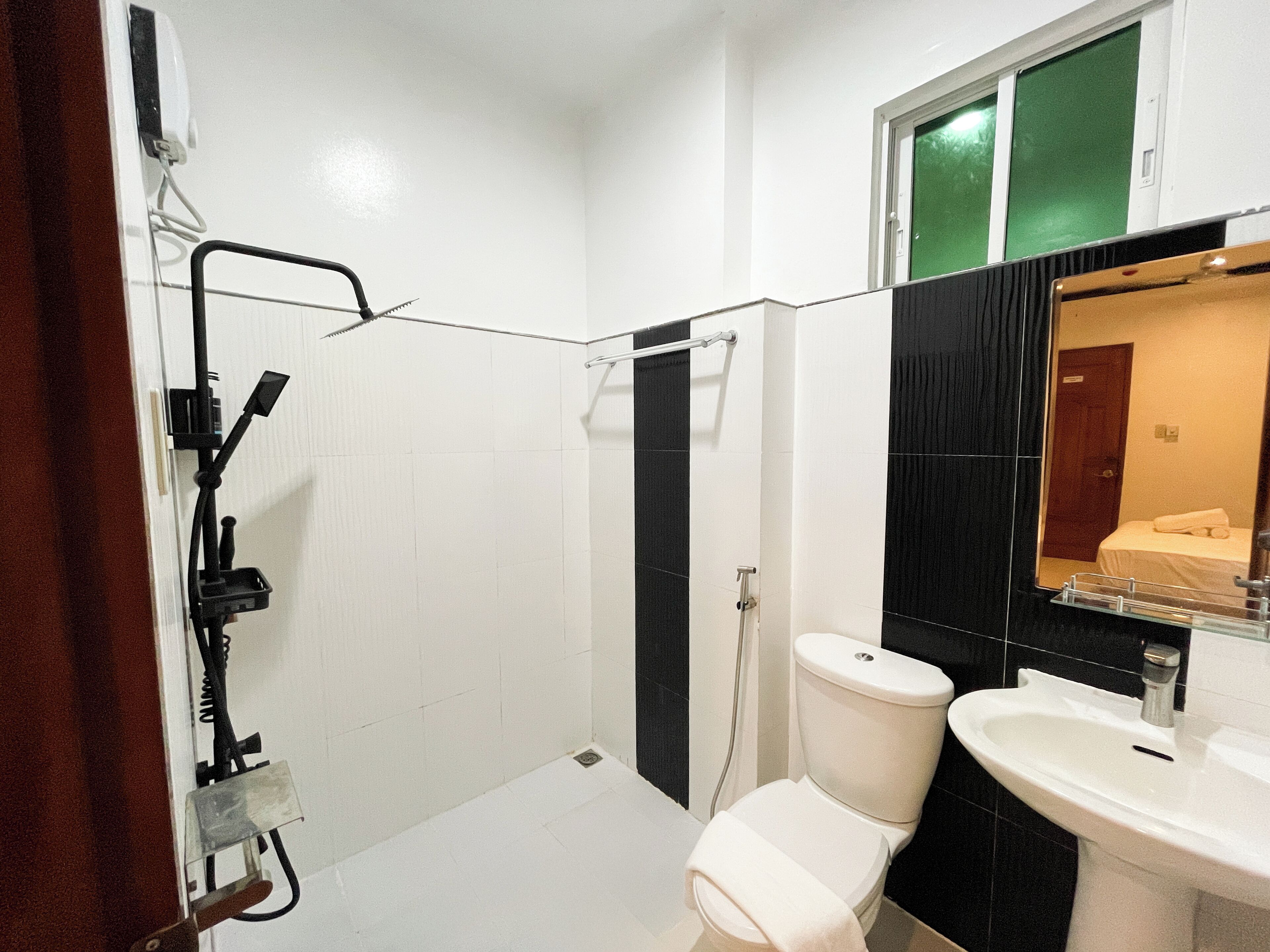 A bathroom with a toilet, sink, shower, and a mirror.