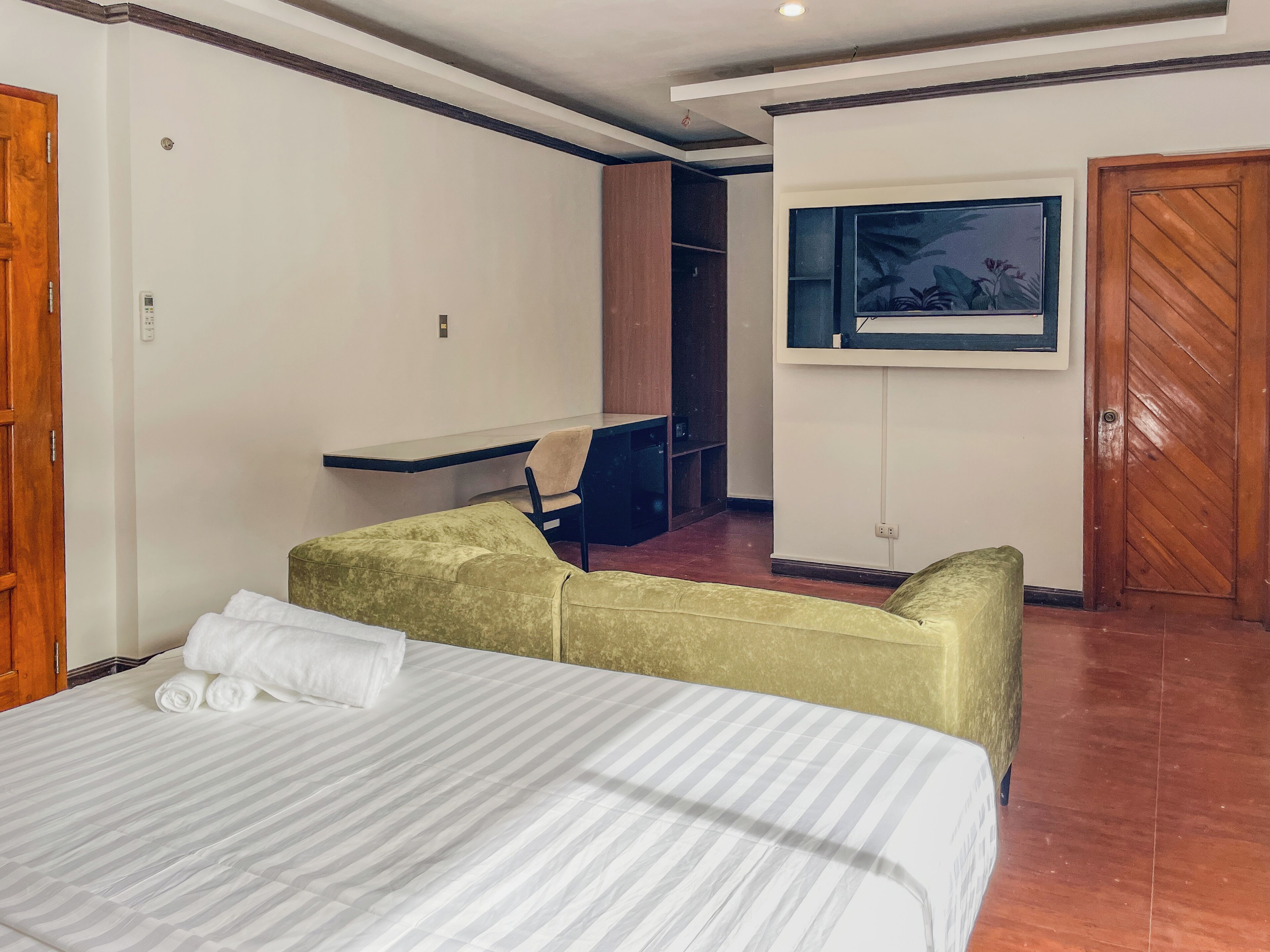 Une chambre d’hôtel avec un lit, un bureau, une chaise, une armoire et un tableau au mur.