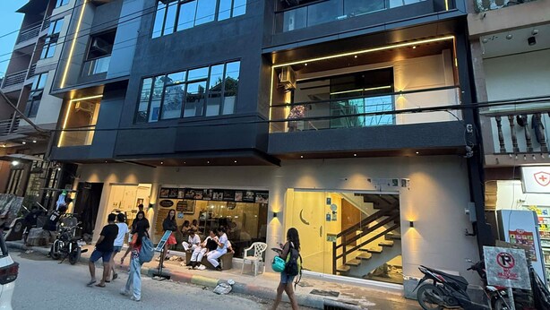 A modern building with multiple floors, large windows, and a ground-level entrance. - The Town  (El Nido)