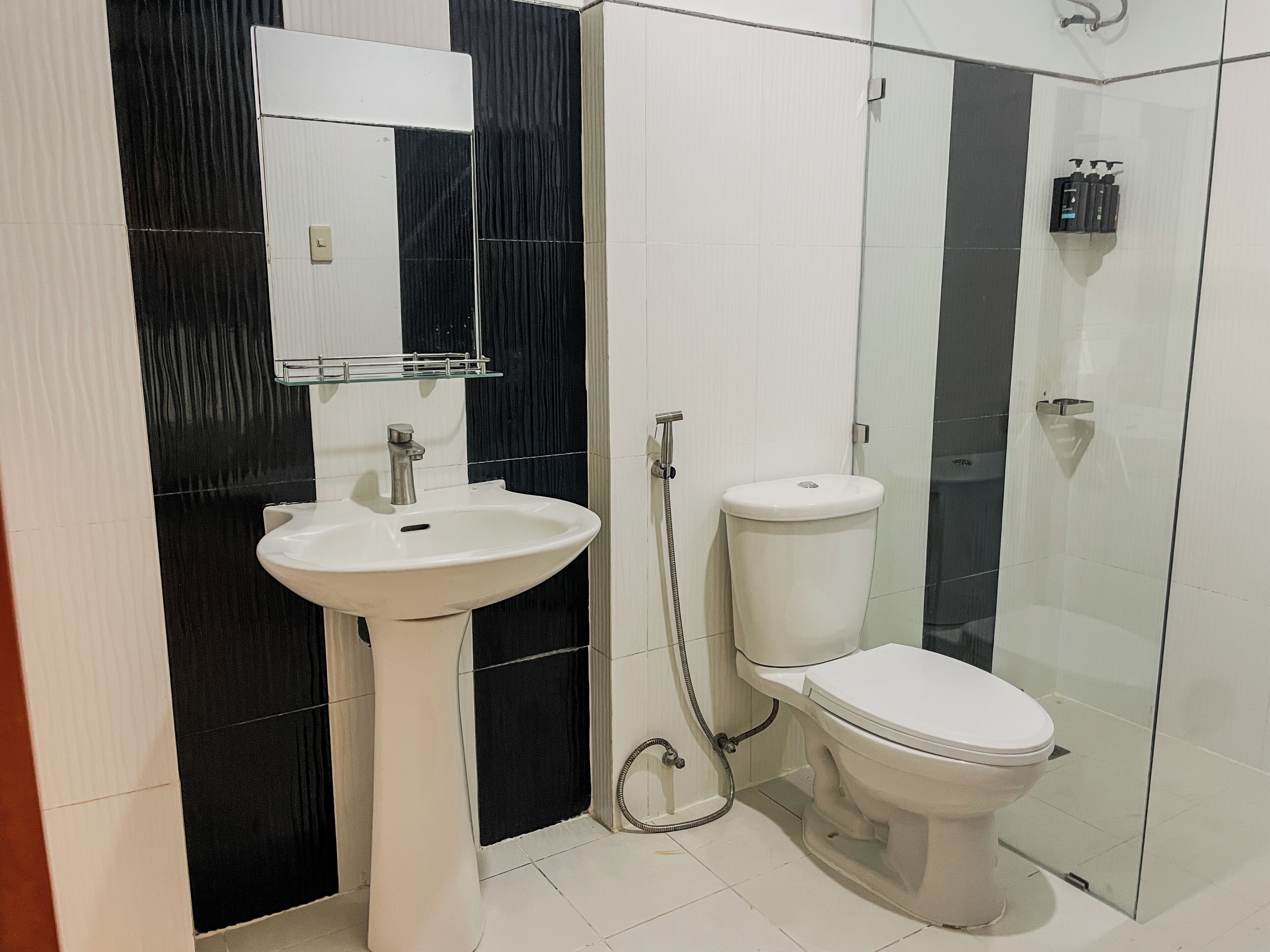 A bathroom with a pedestal sink, a toilet, and a glass shower enclosure.
