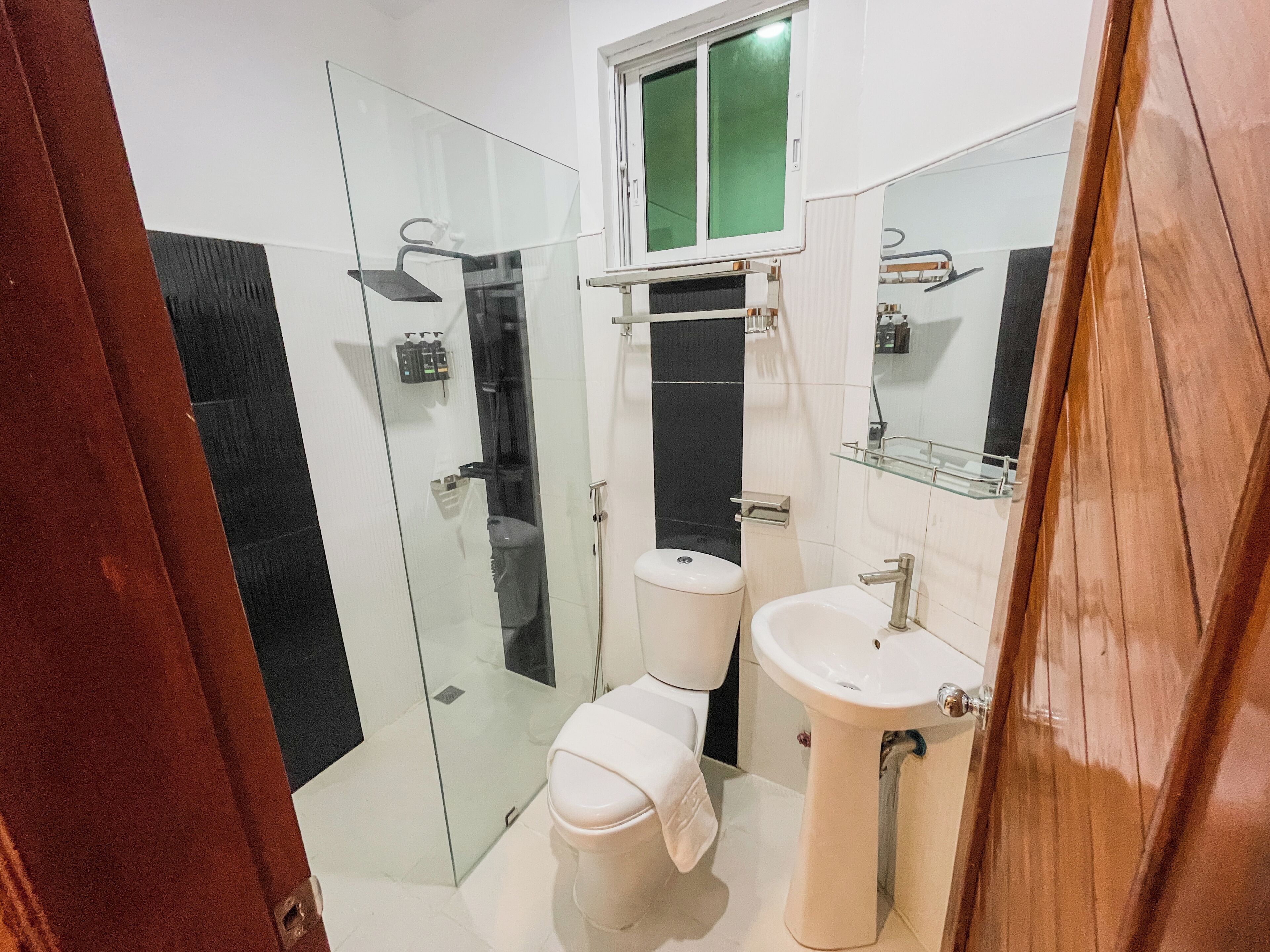 Uma casa de banho moderna com cabine de duche em vidro, sanita e lavatório com espelho em cima.