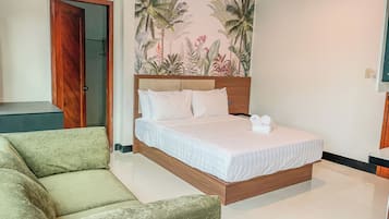 A bedroom with a bed, a green sofa, a wooden door, and a wall with a tropical plant mural.