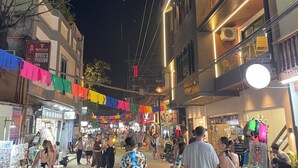 A bustling street scene at night with people walking and shops on either side. - The Town  (El Nido)