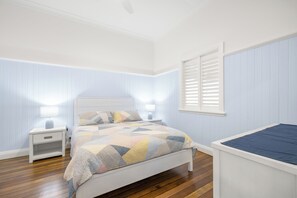 A bedroom with a bed, nightstands, a window with blinds, and wooden flooring. - Kokomo Right in the Heart of South West Rocks (South west rocks)