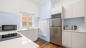 Een moderne keuken met witte kastjes, een roestvrijstalen koelkast, een magnetron en een broodrooster.