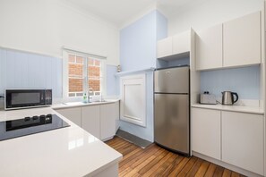 Eine moderne Küche mit weißen Schränken, einem Edelstahlkühlschrank, einer Mikrowelle und einem Toaster.