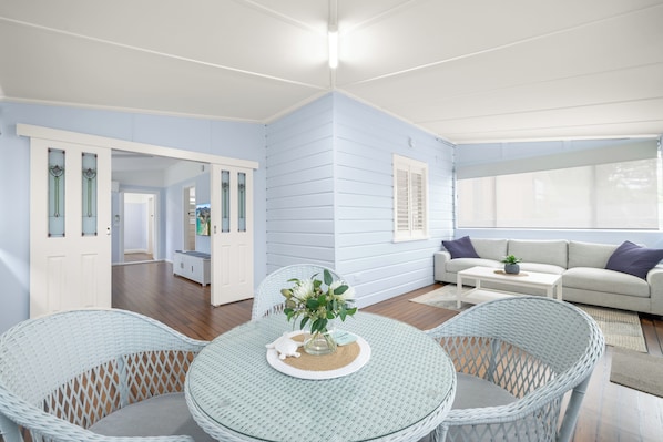 A room with a round glass table, wicker chairs, a sofa, and a view through a window. - Kokomo Right in the Heart of South West Rocks (South west rocks)