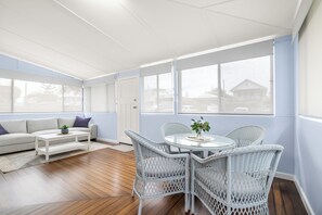 A bright room with a sofa, a round table, wicker chairs, and large windows. - Kokomo Right in the Heart of South West Rocks (South west rocks)