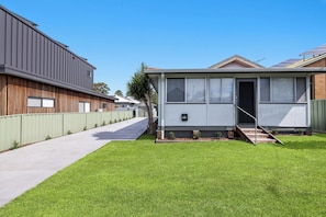 A modern house with a well-maintained lawn, a visible front door, and a small set of stairs leading to the entrance. - Kokomo Right in the Heart of South West Rocks (South west rocks)