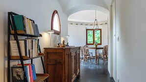 A hallway with a wooden bookshelf, a dining area with chairs, and a window with a view of greenery. - Relax e Natura a Punta Rossa (San Felice Circeo)