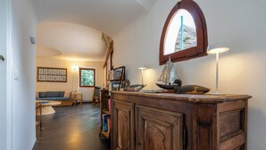 A cozy living room with a wooden cabinet, a bookshelf, and a window with a view. - Relax e Natura a Punta Rossa (San Felice Circeo)