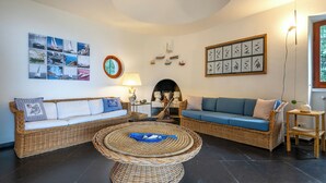 A living room with wicker furniture, a round coffee table, and wall art. - Relax e Natura a Punta Rossa (San Felice Circeo)