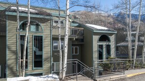 A two-story building with a balcony, a staircase, and a view of mountains. - Riverside Retreat 2 Bedroom Condo (Telluride)