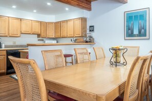 A modern kitchen with wooden cabinets, a dining table with six chairs, and a kitchen island. - Riverside Retreat 2 Bedroom Condo (Telluride)