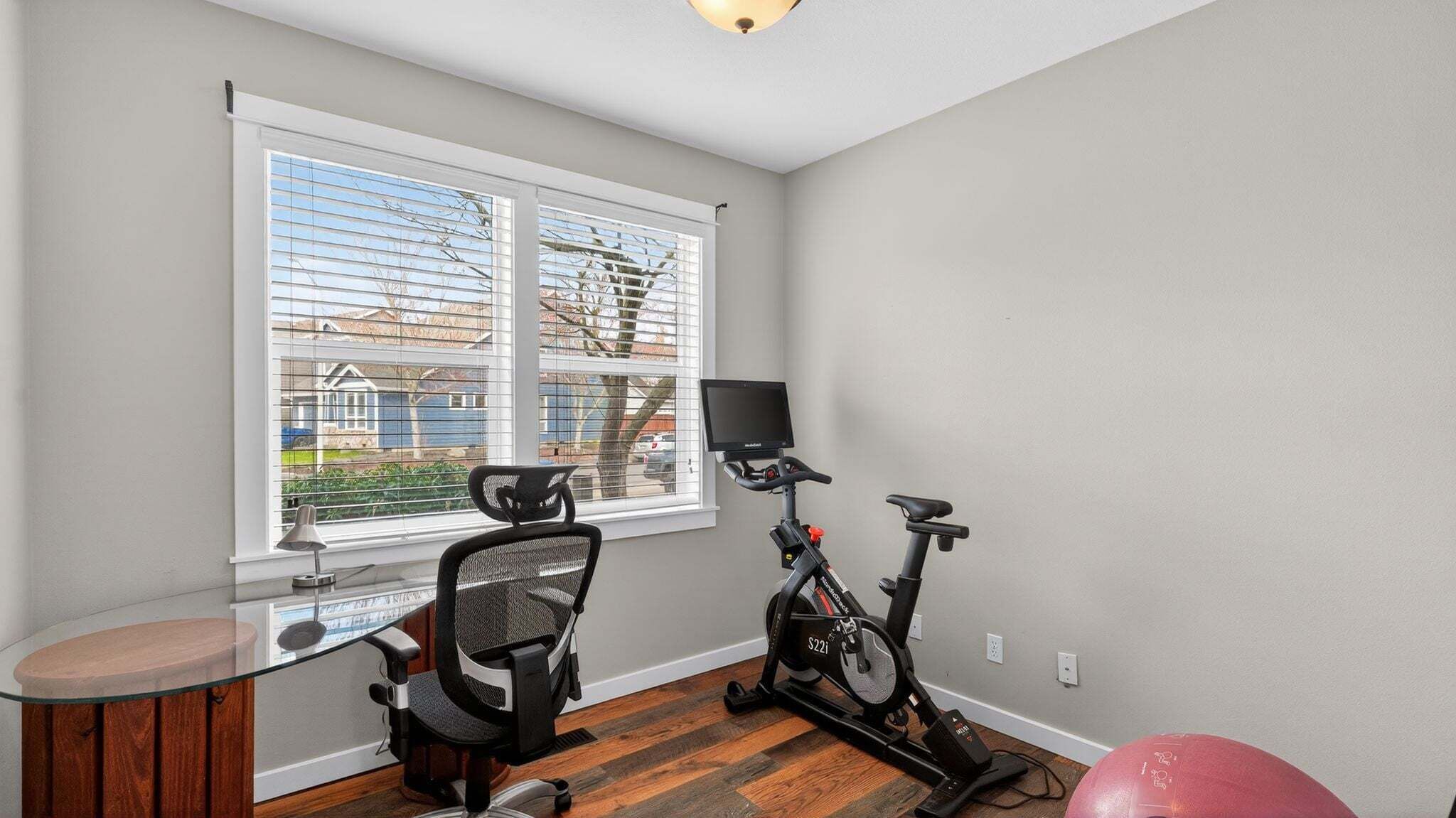 A home office with a desk, chair, and an exercise bike.