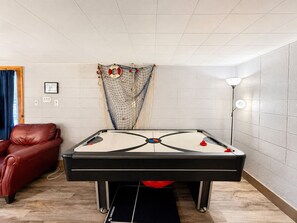 A pool table in a room with a red leather chair, a lamp, and a wall-mounted net. - Little Lake Cove 2 Bedroom Home (Sevierville)