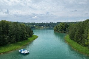 A river with a boat, surrounded by dense greenery and trees. - Little Lake Cove 2 Bedroom Home (Sevierville)