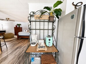 A kitchenette with a coffee maker, a toaster, a kettle, and a sign that reads 'Coffee the Breakfast of Champions.' - Little Lake Cove 2 Bedroom Home (Sevierville)