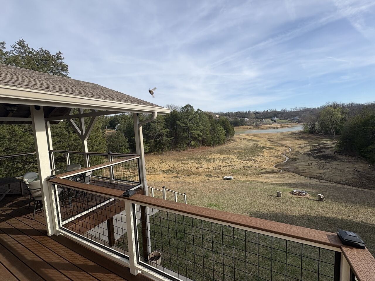 A deck with a view of a river and surrounding landscape.
