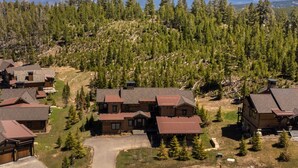 Un albergue con varias cabañas de madera, rodeado de un bosque y montañas al fondo.