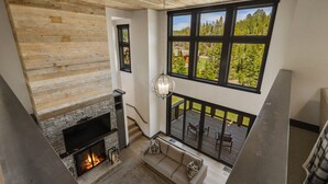 Un interior moderno con chimenea de piedra, techo de madera y un ventanal con vistas al bosque.
