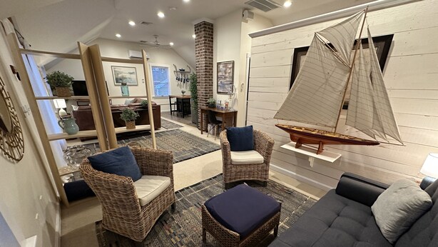 A modern living room with wicker furniture, a sailboat model, and a patterned rug. - 12 Goodwin Unit 2 1 Bedroom Apts (Newport)