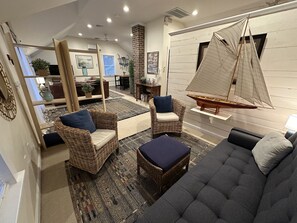 A modern living room with wicker furniture, a sailboat model, and a patterned rug. - 12 Goodwin Unit 2 1 Bedroom Apts (Newport)