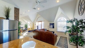 A spacious living area with a large brown leather sofa, a wooden dining table, and a ceiling fan. - 12 Goodwin Unit 2 1 Bedroom Apts (Newport)