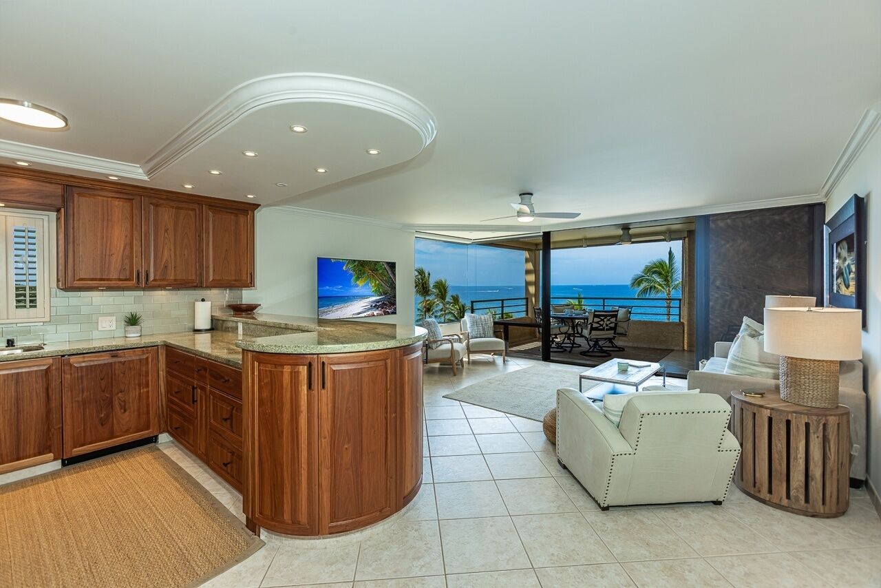 A modern kitchen with wooden cabinets, a central island, and a large TV.