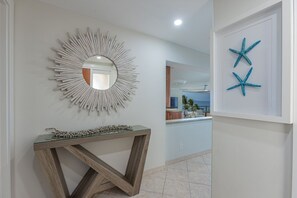 A hallway with a mirror, a console table, and starfish decorations. - Polo Beach Club 703 2 Bedroom Condo (Kihei)